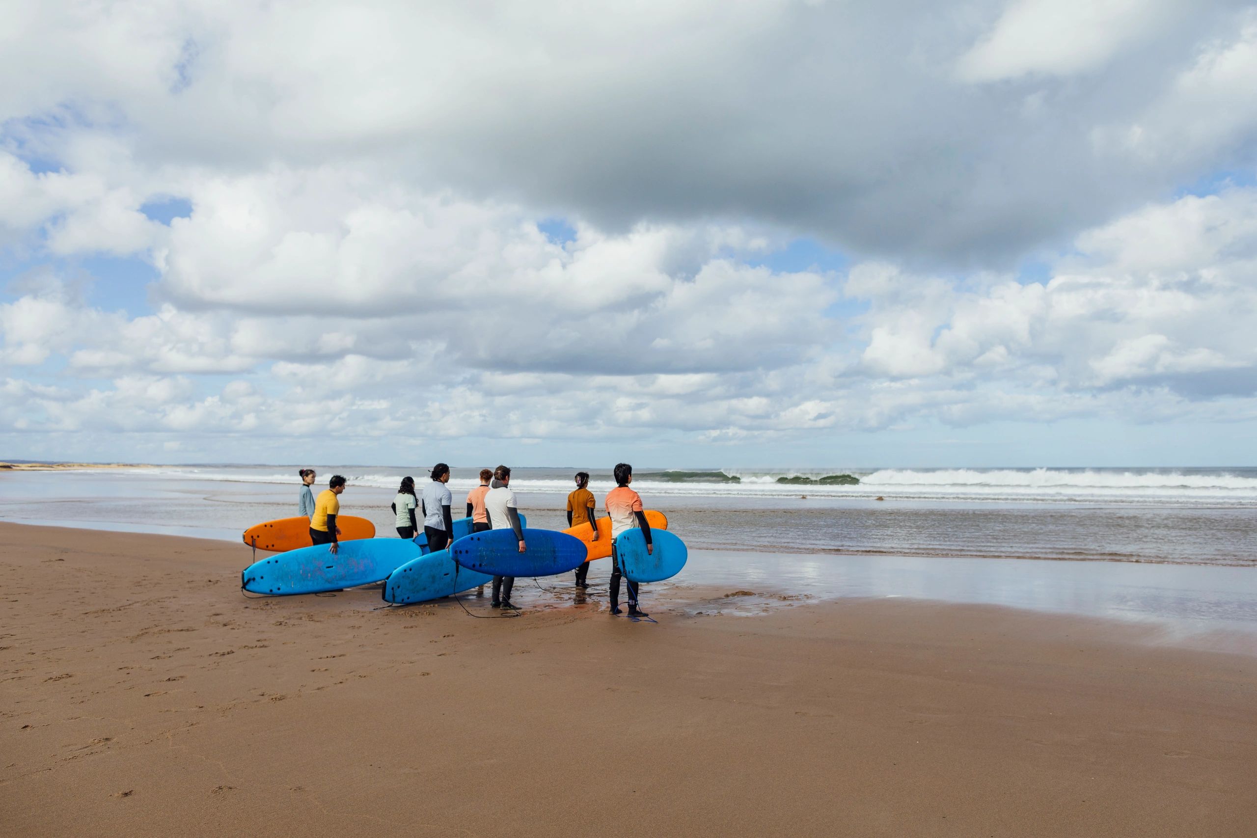 Students carrying surfboards to the water for a lesson