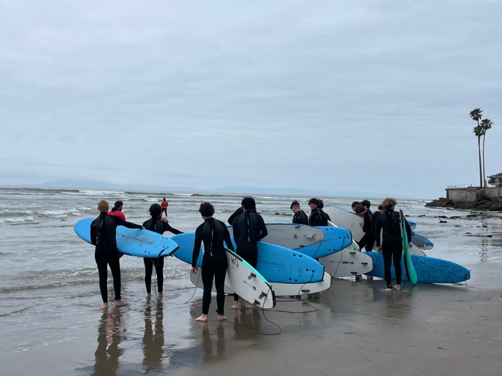 Group of surfers heading into the ocean for a surf lesson in Ventura