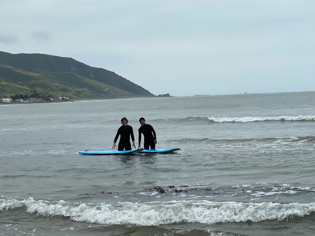 Two surfers standing in the water with their surfboards in Ventura
